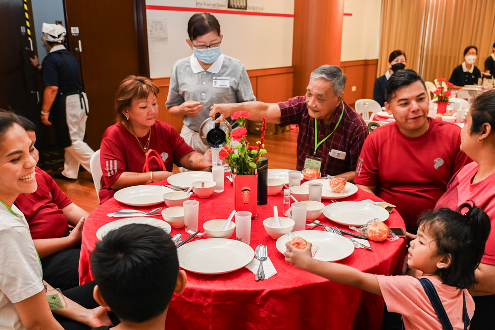 陈良水（右三提茶壶者）、女儿陈玩云（左二）共一家六口来参与新春发放。（摄/ 潘宝通）